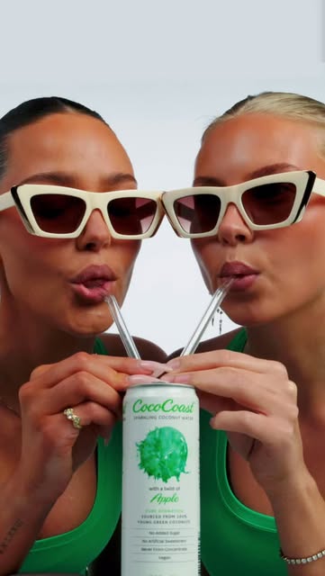 Two models in green drinking CocoCoast sparkling coconut water through straws