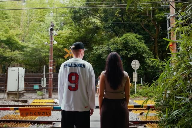 Two people at a railway level crossing surrounded by bamboo in Japan