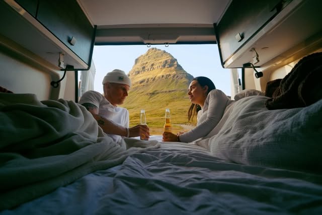 Couple in a camper van with Kirkjufell mountain framed through the open back doors